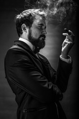 black and white portrait of bearded smoking gentleman in a suit perceptive looking at the cigar