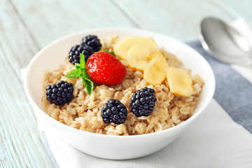 Tasty oatmeal with fruit and berries in bowl on table
