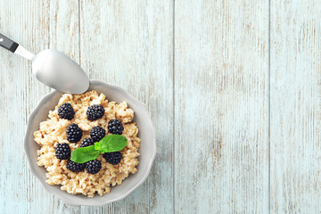 Obraz na płótnie Canvas Tasty oatmeal with berries in bowl on table