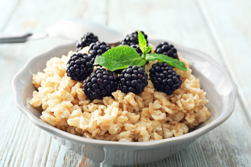 Tasty oatmeal with berries in bowl on table, closeup