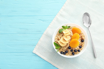 Tasty oatmeal with berries and fruit in bowl on table