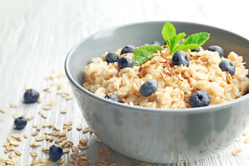 Tasty oatmeal with berries in bowl on table, closeup