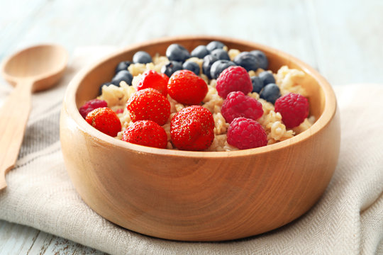 Tasty oatmeal with berries in bowl on table, closeup