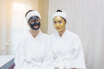 Fototapeta na wymiar Beautiful young Asian women having high quality facial mud mask and high quality and authentic pure gold facial mask waiting for her faces to be cleaned in spa salon