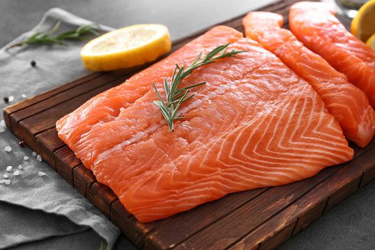 Fresh raw salmon fillet and rosemary on board, closeup