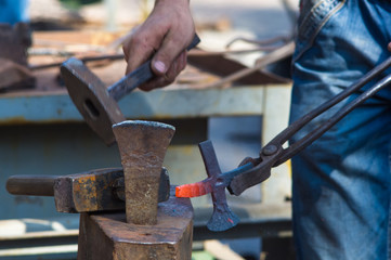 blacksmith performs the forging of hot glowing metal on the anvil