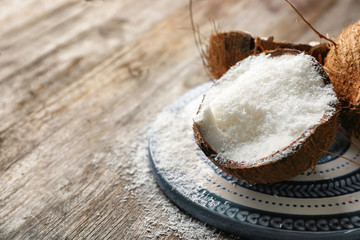 Desiccated coconut in nut on wooden table
