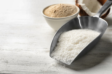 Scoop with desiccated coconut and flour in bowl on white background