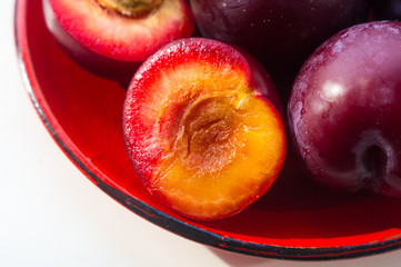 fresh plum fruit in the red saucer on white background
