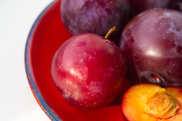 Obraz premium fresh plum fruit in the red saucer on white background