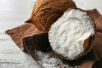 Desiccated coconut in nut on wooden table - obrazy, fototapety, plakaty