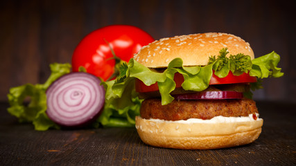 big fresh tasty burger with vegetables on a dark wooden table, hamburger, fast food
