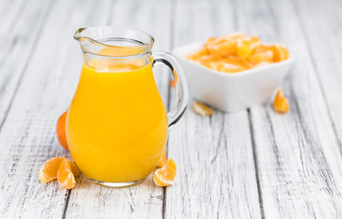 Wooden table with fresh made Tangerine Juice (close-up shot)