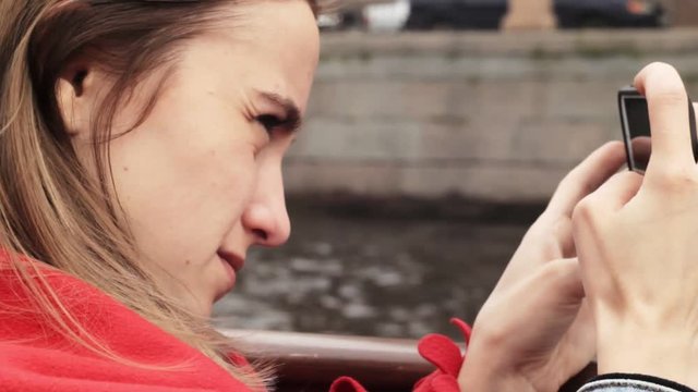 The girl takes pictures from phone, sailing on a boat in St. Petersburg