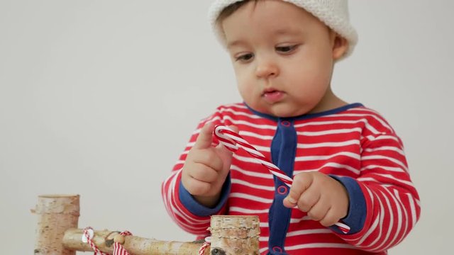 child sits on a small wooden bed in red striped pajamas