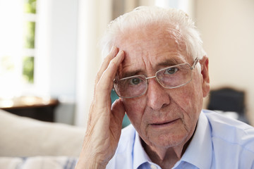 Portrait Of Senior Man Sitting On Sofa Suffering From Depression