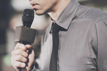 Naklejka premium A man holds a microphone and speaks into it