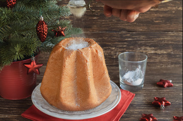 Delicious Christmas cake Pandoro with  vanilla scente icing sugar traditiolly consumed at Christmas times in Italy. Italian sweet yeast bread with christmas decoration on wooden background.