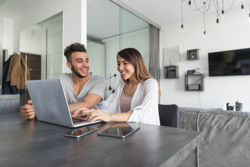 Couple Use Laptop Computer Sitting At Table In Modern Apartment Together Young Man And Woman Surf Internet Happy Smiling
