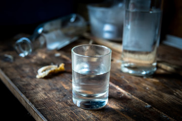 A small stack of vodka close up on the old dirty wooden table - obrazy, fototapety, plakaty