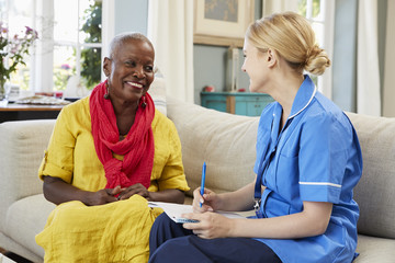 Obraz premium Female Community Nurse Visits Senior Woman At Home