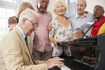 Group Of Seniors Standing By Piano And Singing Together © Monkey Business