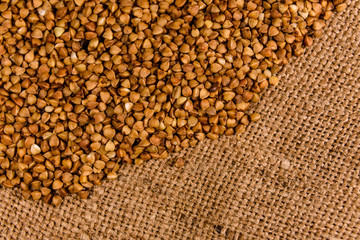 Pile of the raw buckwheat on sackcloth. Top view