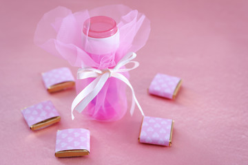Soap bubble bottle and small chocolates on color background