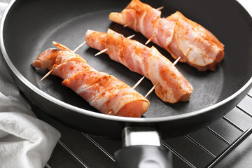 Frying pan with bacon wrapped chicken nuggets on table, closeup