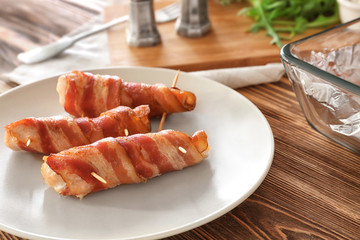 Plate with bacon wrapped chicken nuggets on table