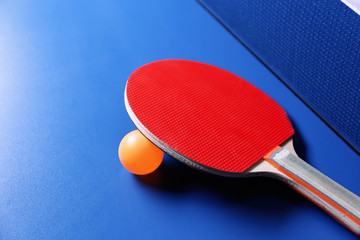 Ping pong racket and ball near net on table