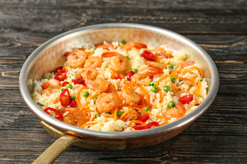 Frying pan with delicious shrimp fried rice on wooden table