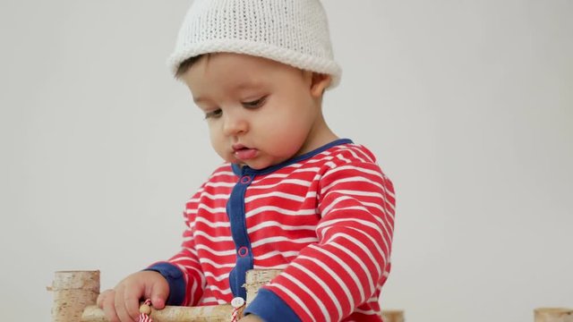 child sits on a small wooden bed in red striped pajamas