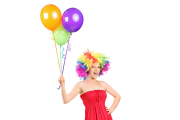 Fototapeta na wymiar Girl with a wig holding a bunch of balloons