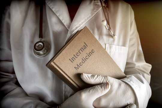 Doctor Holds In An Internal Medicine Book In A Hospital. Conceptual Image