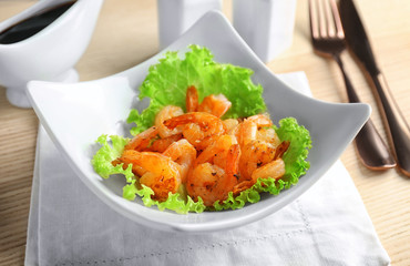 Plate with delicious grilled shrimps on table