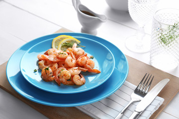 Plate with delicious grilled shrimps on table