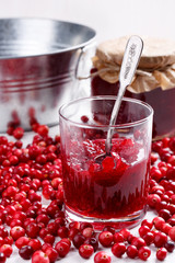 Red cranberry jam in glass on white table