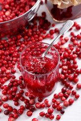 Red cranberry jam in glass on white table