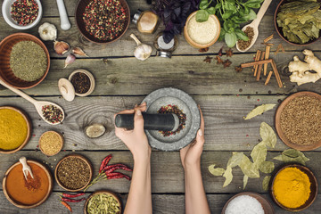 woman grinding pepper with pestle and mortar - obrazy, fototapety, plakaty
