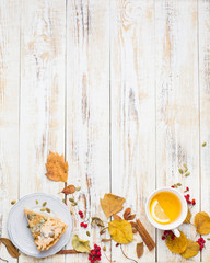Autumn background with pumpkin pie, hot tea, yellowed leaves, book and rug. Perfect sunny autumn. A wooden light white autumn background for you. Copy Space. Place for text. Flat lay, top view