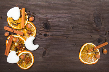 Christmas background: white gingerbread cookies, dried orange, cinamon, anise and cloves on dark brown wooden plank, copy space
