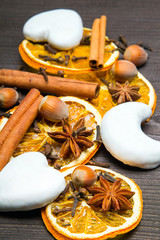 Christmas background: white gingerbread cookies, dried orange, cinamon, anise and cloves on dark brown wooden plank, copy space