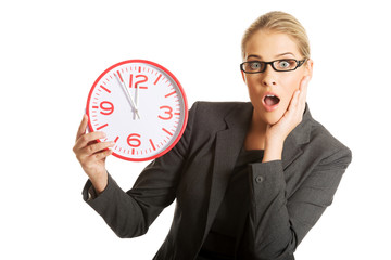 Surprised businesswoman holding a big clock
