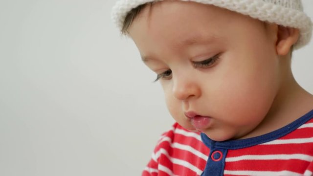 child sits on a small wooden bed in red striped pajamas