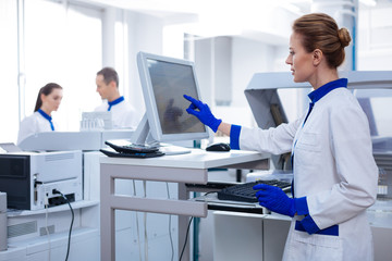 Science for women.  Blond beautiful female researcher filling medical chart while looking at the screen and  standing in the lab