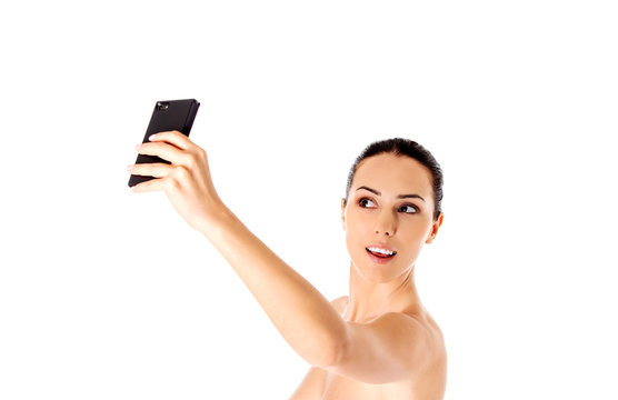 Nude beautiful woman taking selfie on white background.