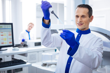 One more drop. Skillful attractive male madical worker dropping medication with a pipette into vial...