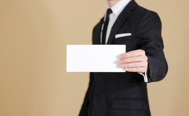 Man showing blank black flyer brochure booklet. Leaflet presentation. Pamphlet hold hands. Man show clear offset paper. Sheet template. Man in a black suit, white shirt and tie.