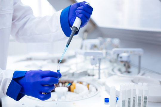 Parental test. Hands in blue gloves holding pipette and test tube with poured blue chemical  which placed on blurred background